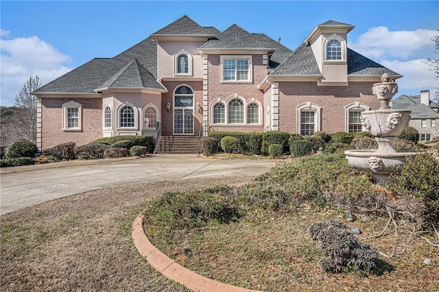 view of front of property with brick siding, roof with shingles, and stucco siding