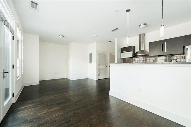 kitchen featuring dark hardwood / wood-style flooring, wall chimney range hood, hanging light fixtures, and tasteful backsplash