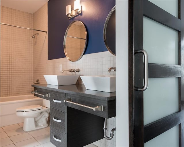 full bathroom featuring vanity, tile patterned floors, tiled shower / bath combo, toilet, and tile walls