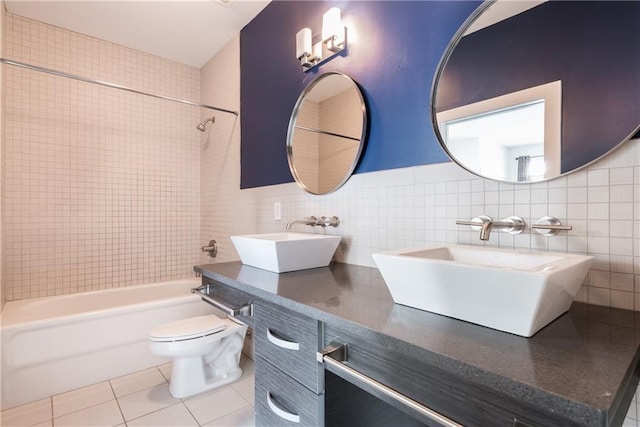 full bathroom featuring tile patterned floors, toilet, vanity, tile walls, and tiled shower / bath