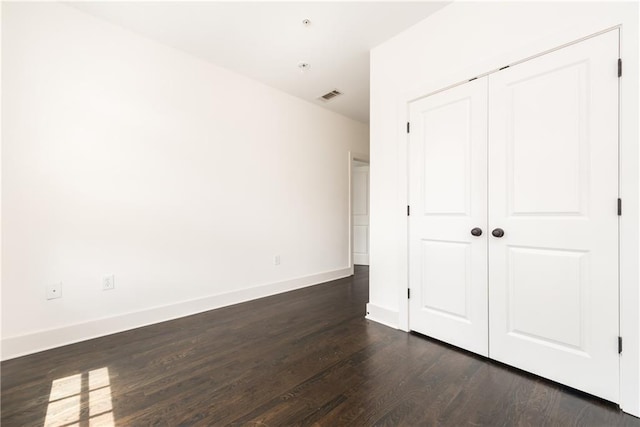 unfurnished bedroom with dark wood-type flooring and a closet