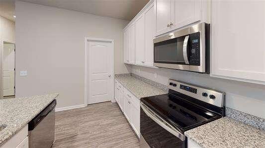 130 Thornwood Dr SW, Rome, GA 30165 - kitchen with appliances with stainless steel finishes, white cabinets, light wood-style floors, and light stone countertops
