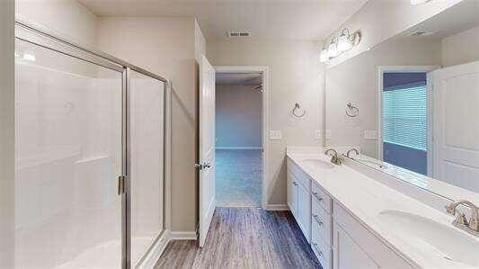 130 Thornwood Dr SW, Rome, GA 30165 - bathroom featuring wood finished floors, a shower stall, double vanity, and baseboards