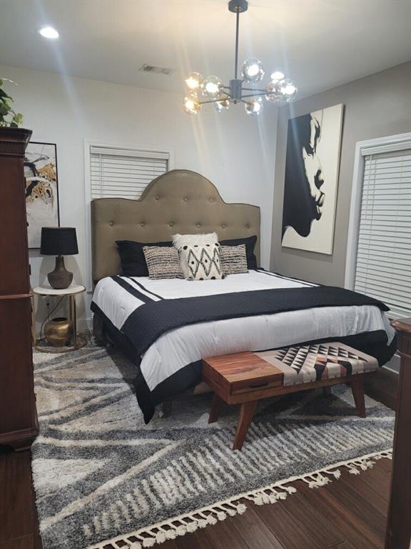 bedroom with wood-type flooring and a notable chandelier