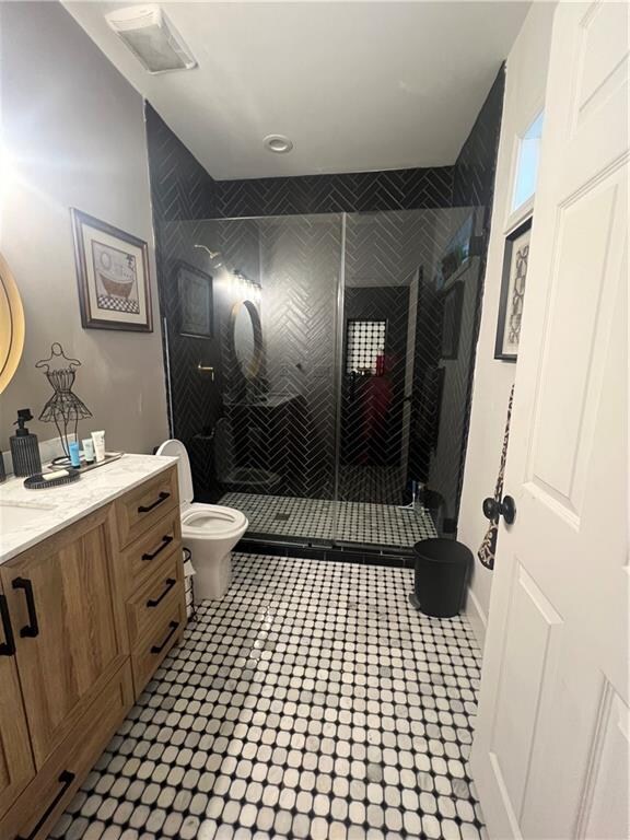 bathroom with vanity, toilet, a shower with door, and tile patterned flooring