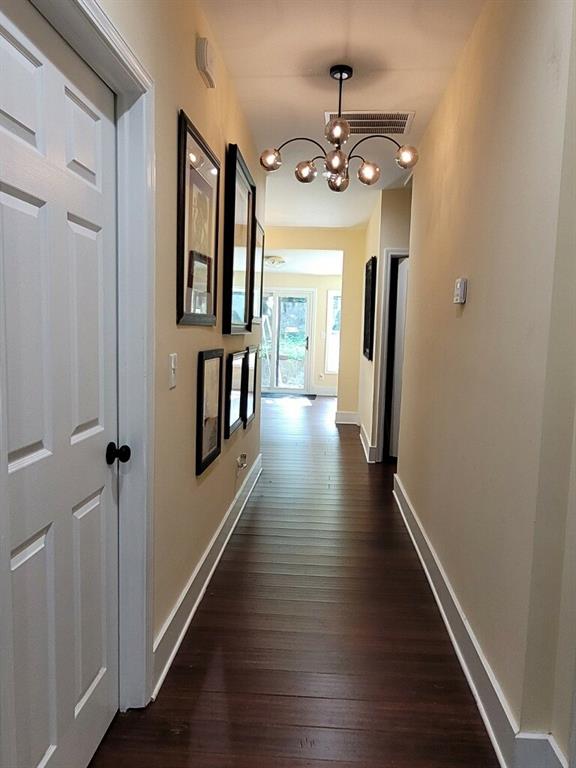 corridor featuring dark wood-type flooring and a notable chandelier