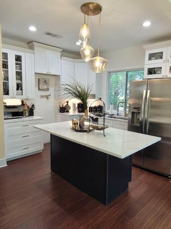 kitchen with a kitchen island, dark hardwood / wood-style floors, white cabinets, and stainless steel fridge