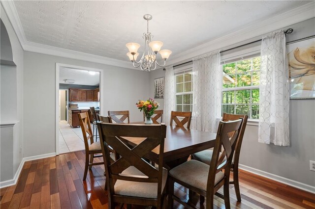dining room with baseboards, an inviting chandelier, ornamental molding, and light wood finished floors