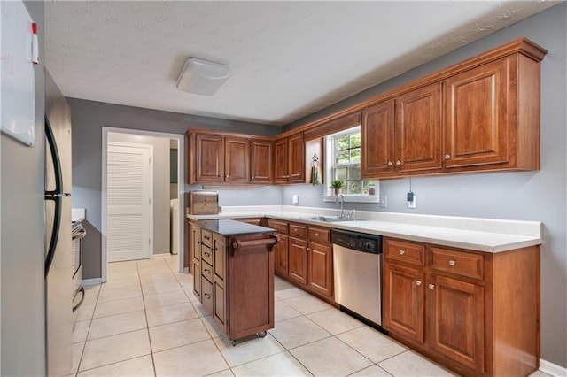 kitchen with brown cabinetry, a sink, appliances with stainless steel finishes, and a center island