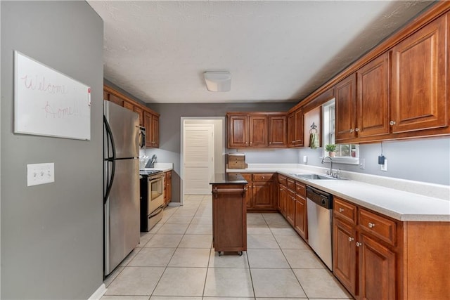 kitchen featuring a sink, light tile patterned floors, brown cabinets, and stainless steel appliances