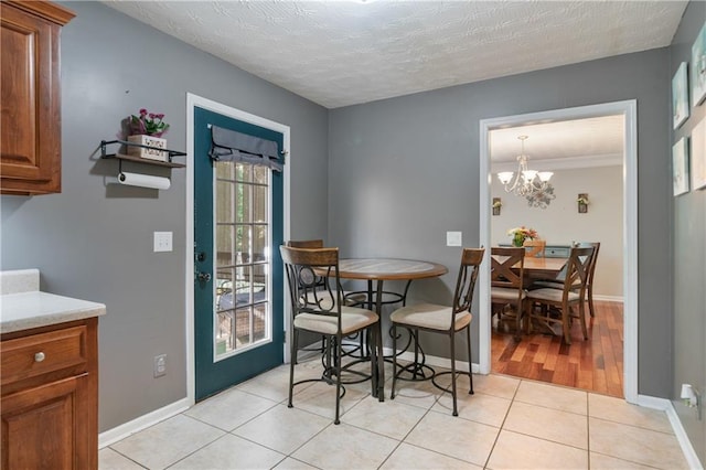 dining area featuring an inviting chandelier, a textured ceiling, baseboards, and light tile patterned floors