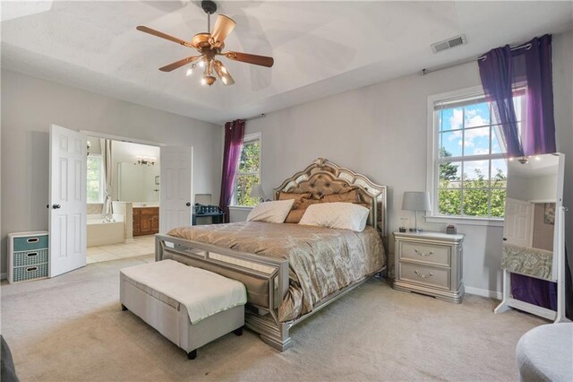 bedroom featuring visible vents, light carpet, ensuite bathroom, and multiple windows