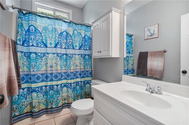 bathroom with toilet, curtained shower, tile patterned flooring, and vanity