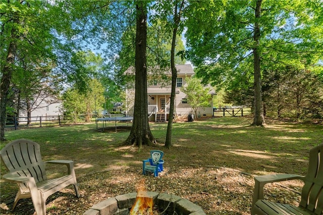 view of yard with a fenced backyard, a trampoline, and a fire pit