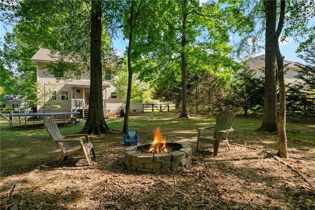 view of yard featuring a trampoline and an outdoor fire pit