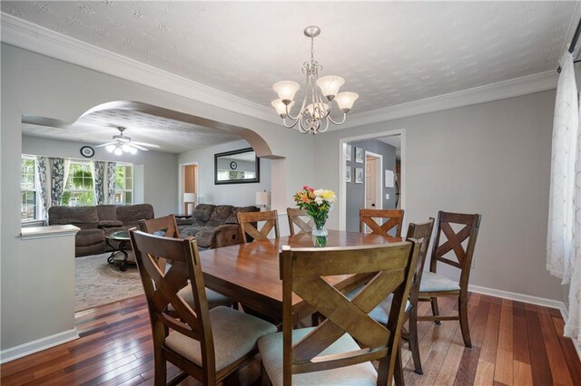 dining space featuring arched walkways, baseboards, ceiling fan with notable chandelier, and hardwood / wood-style flooring
