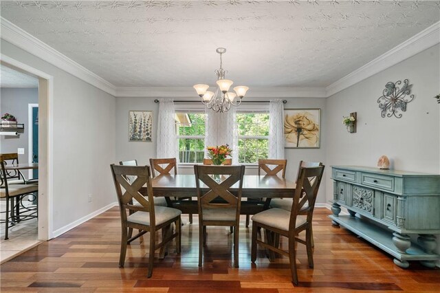 dining area with crown molding, baseboards, an inviting chandelier, and hardwood / wood-style flooring