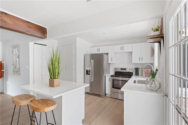 kitchen featuring a kitchen breakfast bar, sink, light hardwood / wood-style flooring, white cabinetry, and stainless steel appliances