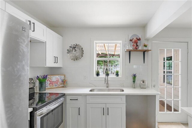 kitchen featuring sink, white cabinetry, stainless steel appliances, and tasteful backsplash