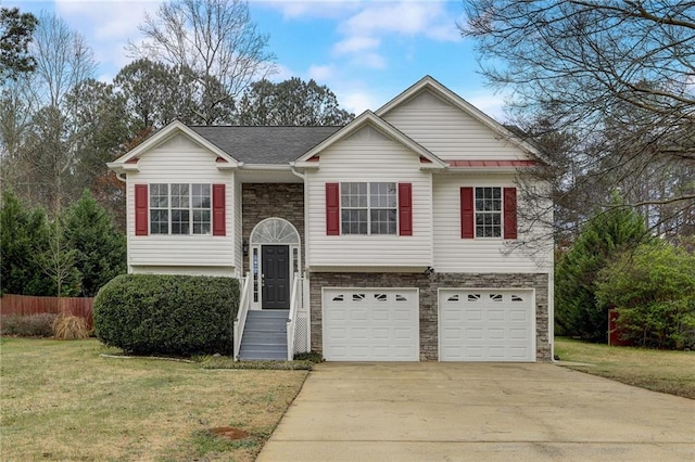 raised ranch featuring a garage and a front lawn