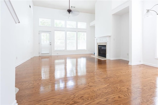 3277 Wyesham Cir, Duluth, GA 30096 - unfurnished living room with a ceiling fan, wood finished floors, a glass covered fireplace, a high ceiling, and baseboards