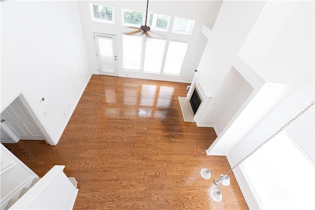 3277 Wyesham Cir, Duluth, GA 30096 - unfurnished living room with wood finished floors, ceiling fan, a fireplace with flush hearth, a high ceiling, and baseboards