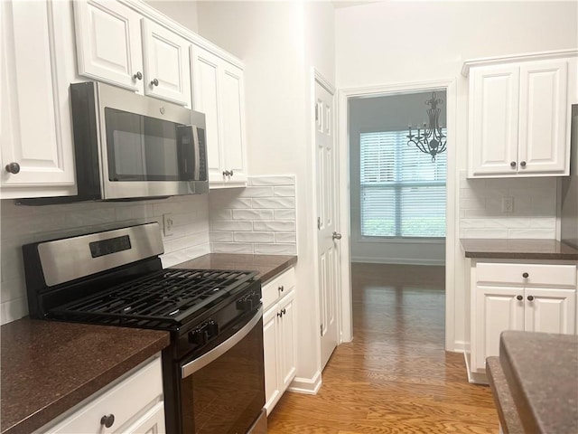 3277 Wyesham Cir, Duluth, GA 30096 - kitchen featuring appliances with stainless steel finishes, light wood-style floors, white cabinetry, decorative backsplash, and a chandelier