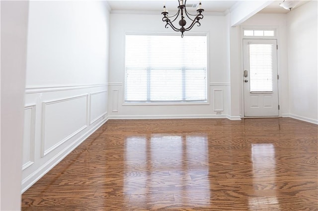 3277 Wyesham Cir, Duluth, GA 30096 - unfurnished dining area with a chandelier, a decorative wall, plenty of natural light, crown molding, and wood finished floors