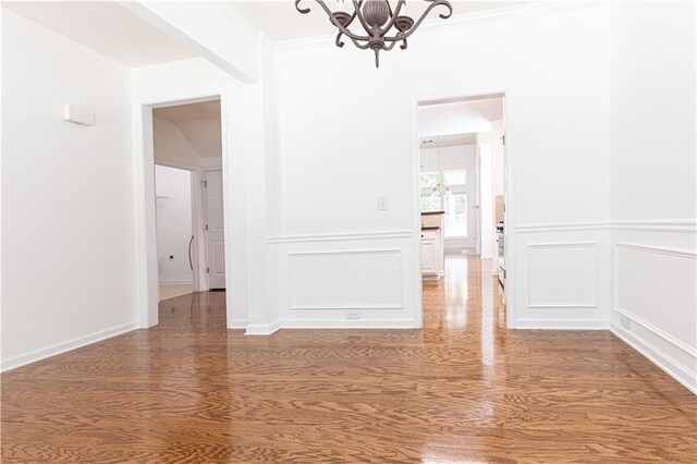 3277 Wyesham Cir, Duluth, GA 30096 - unfurnished dining area with a chandelier, wood finished floors, a decorative wall, crown molding, and wainscoting