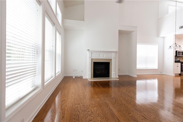 3277 Wyesham Cir, Duluth, GA 30096 - unfurnished living room featuring a high ceiling, a fireplace with raised hearth, wood finished floors, and plenty of natural light