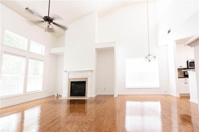 3277 Wyesham Cir, Duluth, GA 30096 - unfurnished living room featuring high vaulted ceiling, ceiling fan, a glass covered fireplace, light wood finished floors, and a chandelier
