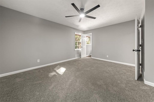 unfurnished bedroom featuring ceiling fan, dark carpet, and a textured ceiling