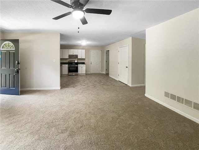 unfurnished living room with ceiling fan and dark colored carpet