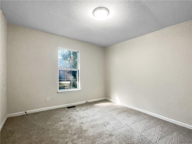 carpeted empty room featuring a textured ceiling