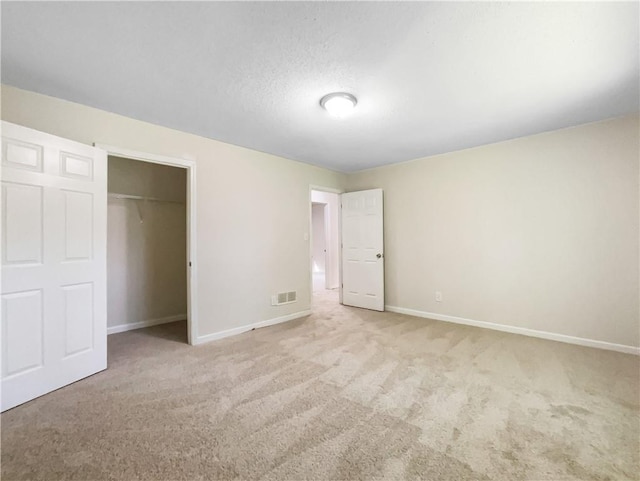 unfurnished bedroom featuring a textured ceiling, a closet, and light carpet