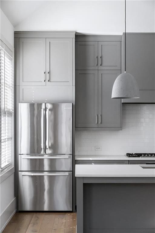 kitchen featuring decorative backsplash, a wealth of natural light, gray cabinetry, stainless steel appliances, and light hardwood / wood-style floors