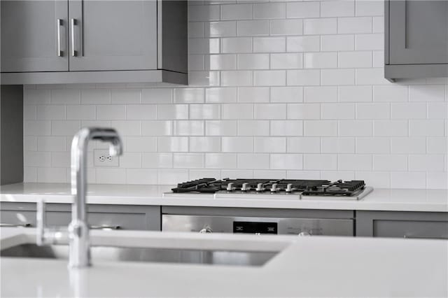 kitchen featuring backsplash, gray cabinetry, and stainless steel gas cooktop