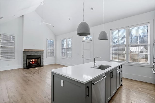 kitchen with pendant lighting, stainless steel dishwasher, sink, and an island with sink