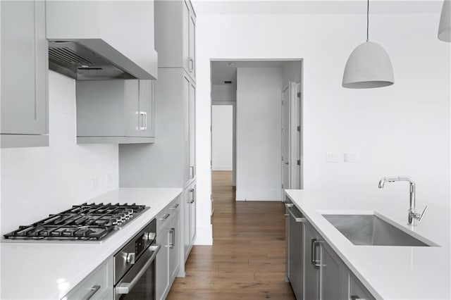 kitchen featuring sink, hanging light fixtures, wall chimney exhaust hood, appliances with stainless steel finishes, and dark hardwood / wood-style flooring