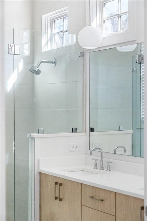 bathroom featuring a shower with door, vanity, and a healthy amount of sunlight