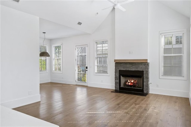 unfurnished living room with high vaulted ceiling, hardwood / wood-style flooring, a stone fireplace, and ceiling fan