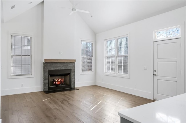 unfurnished living room with ceiling fan, a fireplace, high vaulted ceiling, and wood-type flooring