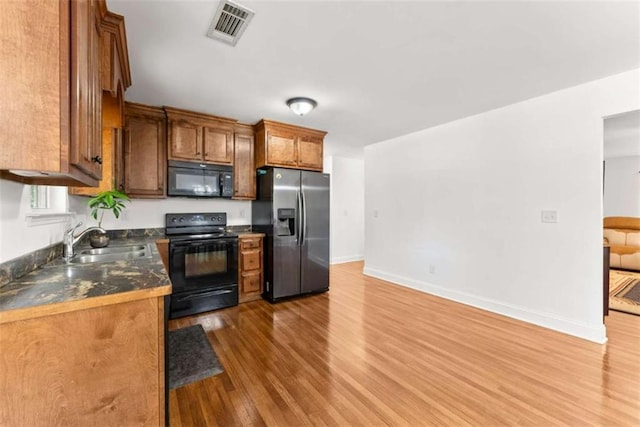 kitchen with sink, black appliances, and dark hardwood / wood-style floors