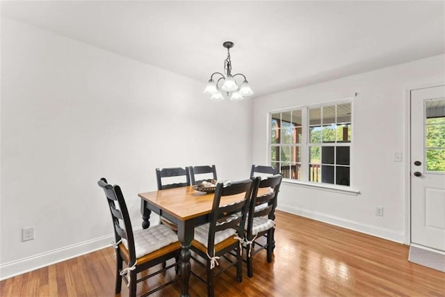 dining space with hardwood / wood-style floors and a notable chandelier