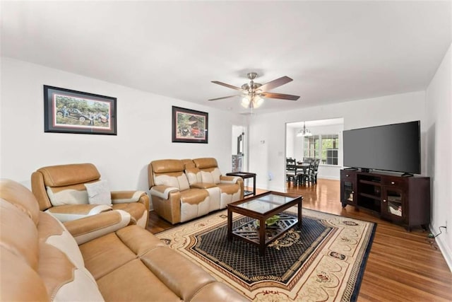 living room with ceiling fan with notable chandelier and hardwood / wood-style floors