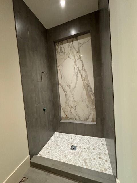 full bath featuring baseboards and tiled shower
