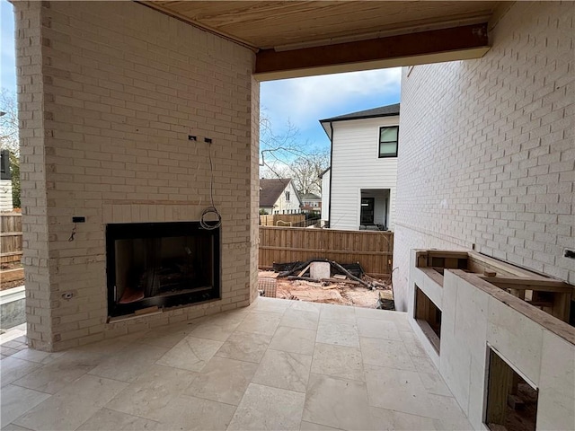 view of patio / terrace with an outdoor brick fireplace and fence