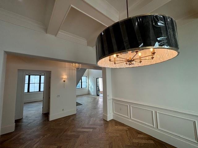 interior space featuring beamed ceiling, wainscoting, baseboards, and an inviting chandelier