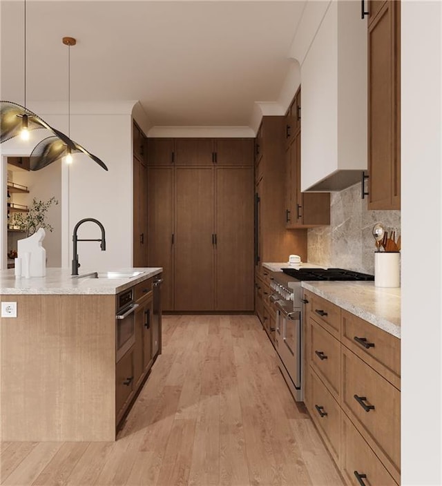 kitchen featuring a sink, light wood-style floors, ornamental molding, appliances with stainless steel finishes, and tasteful backsplash