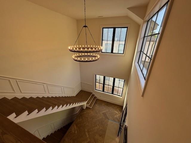 staircase featuring a chandelier and baseboards